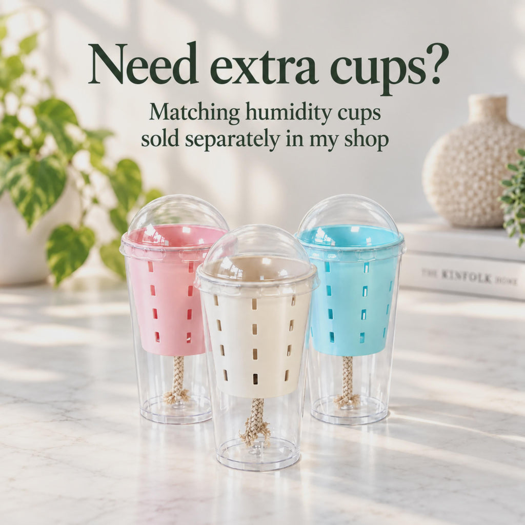 Three humidity cups with pink, beige and baby blue slotted inner pots, transparent dome lids and beige cotton wicks extending into clear lower reservoirs. Text explains that matching additional cups are sold separately in the shop.