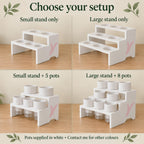 Comparison of small two-tier and large three-tier plant stands, shown empty and with white self-watering pots. The small stand has five openings and the large eight. Included pots have semi-clear reservoirs; text notes that pots are supplied in white.