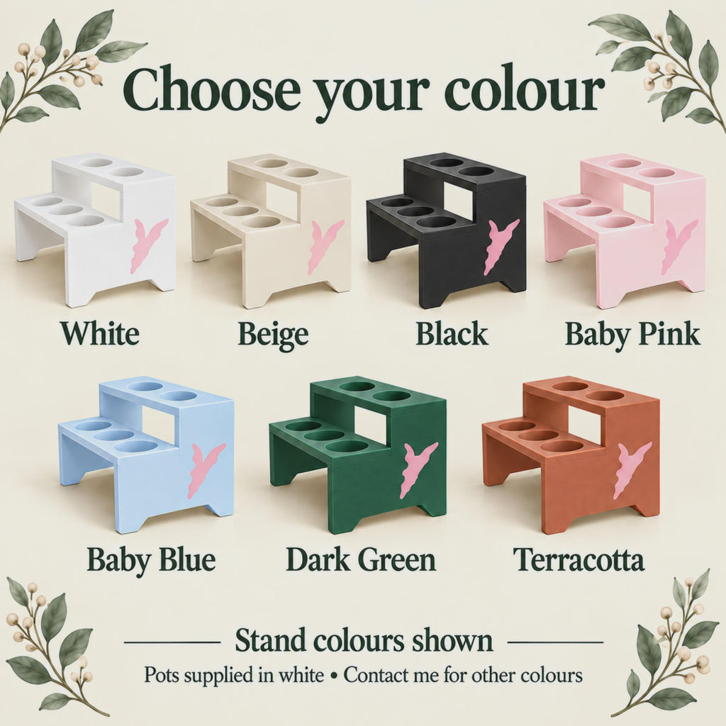 Seven open-front, open-back plant stands in White, Beige, Black, Baby Pink, Baby Blue, Dark Green and Terracotta. Each has two shelves with five circular pot openings and a pink side logo. Text notes that bundled pots are supplied in white.