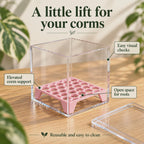 Pink square corm riser inside a clear acrylic box, showing the elevated platform, openings for root growth and removable insert.