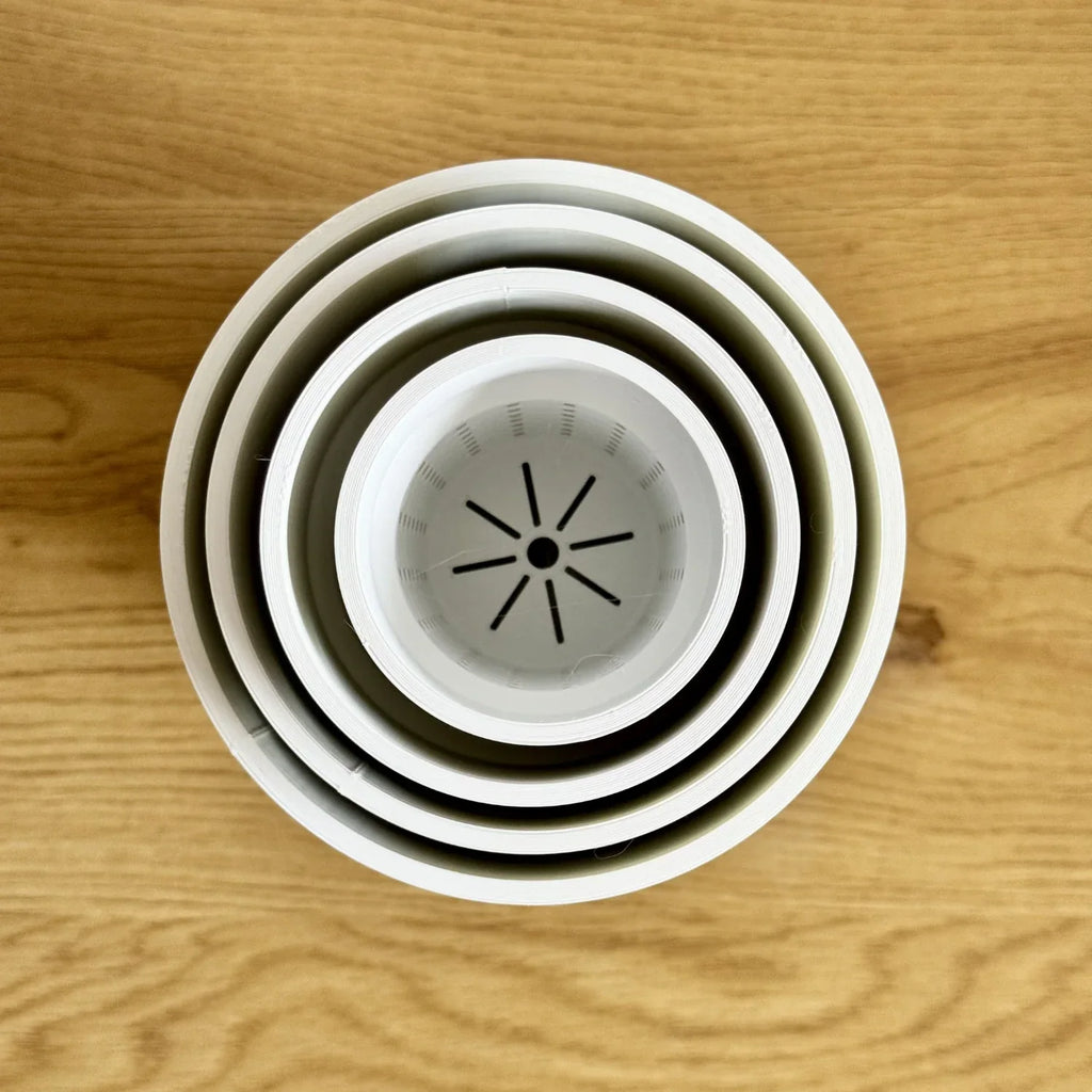 Stacked 3D printed plant pots with drainage holes on wood surface, top view